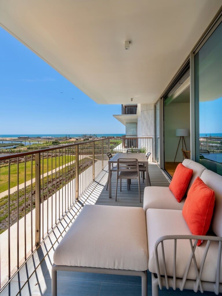 bliss & spa balcony at Bayline, Armação de Pêra: lounge sofa with coral cushions and dining table, view towards the sea