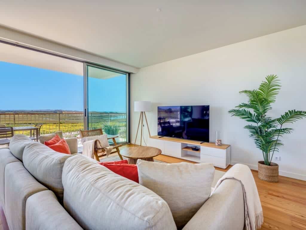 bliss & spa living room at Bayline, Armação de Pêra: sofa with coral cushions, TV and glass doors to the balcony