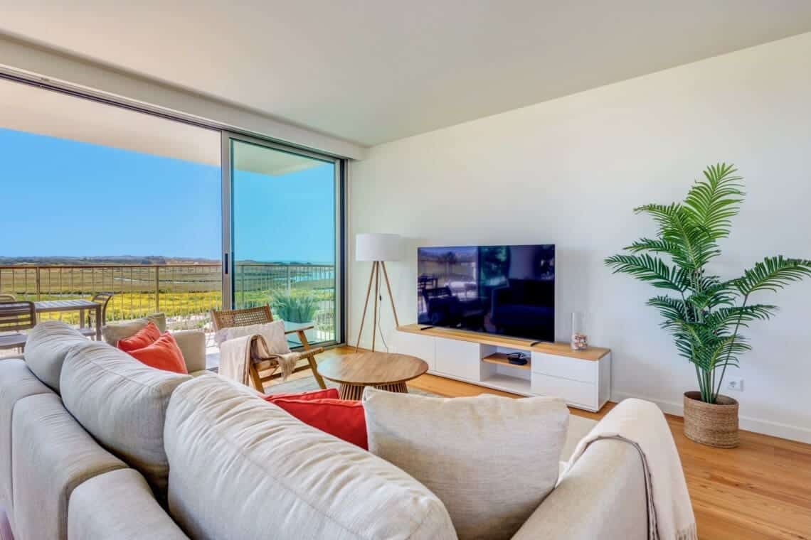 bliss & spa living room at Bayline, Armação de Pêra: sofa with coral cushions, TV and glass doors to the balcony