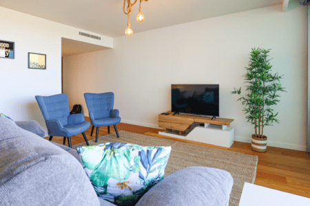 Salmão living room at Bayline, Armação de Pêra: grey sofa with tropical cushion, blue armchairs and TV