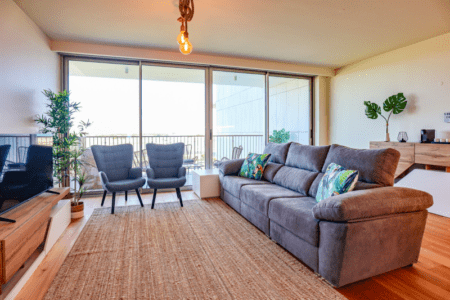 Salmão living room at Bayline, Armação de Pêra: grey sofa, blue armchairs and floor-to-ceiling windows
