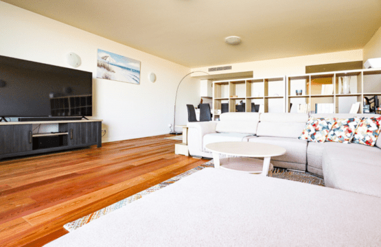 Cavala living room at Bayline, Armação de Pêra: white corner sofa, round coffee table, TV and dining area