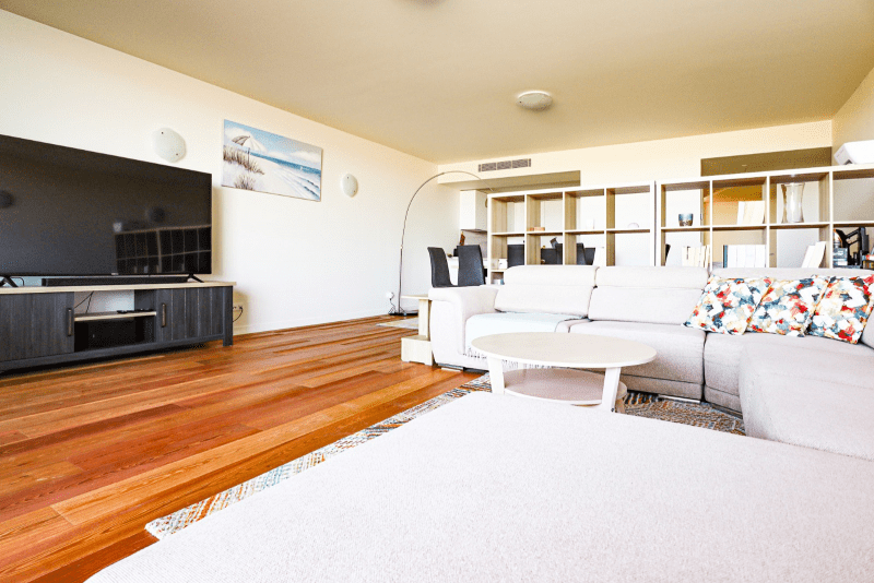 Cavala living room at Bayline, Armação de Pêra: white corner sofa, round coffee table, TV and dining area