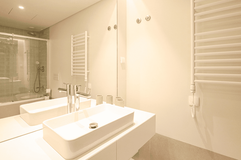 Cavala bathroom at Bayline, Armação de Pêra: vessel basin, heated towel rail and bathtub reflected in the mirror