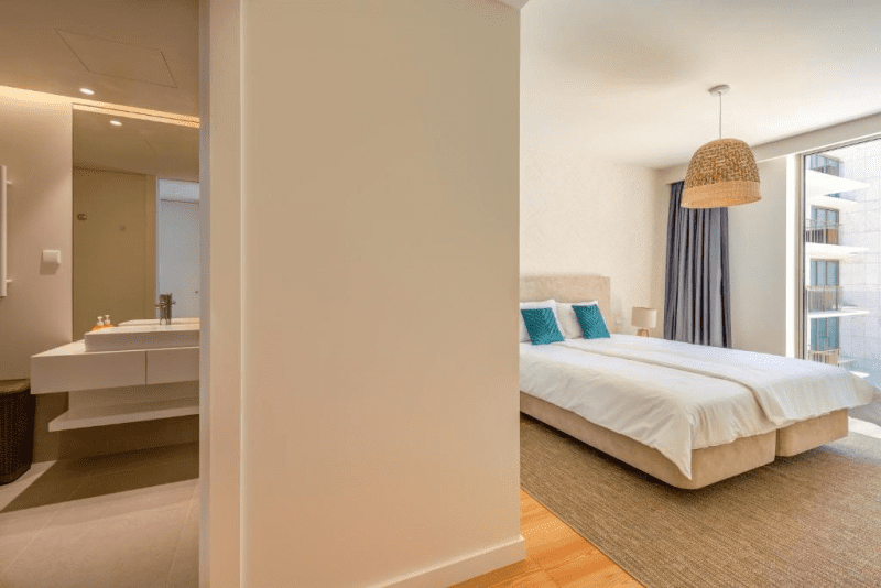 Pargo A bedroom at Bayline, Armação de Pêra: double bed with teal cushions and en-suite bathroom alongside