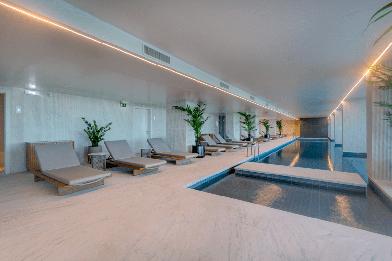 Bayline condominium indoor pool in Armação de Pêra: pool with loungers and potted palms along the side