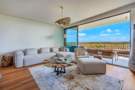 Raia living room at Bayline, Armação de Pêra: white sofa, ottoman and glass doors to the balcony with open views