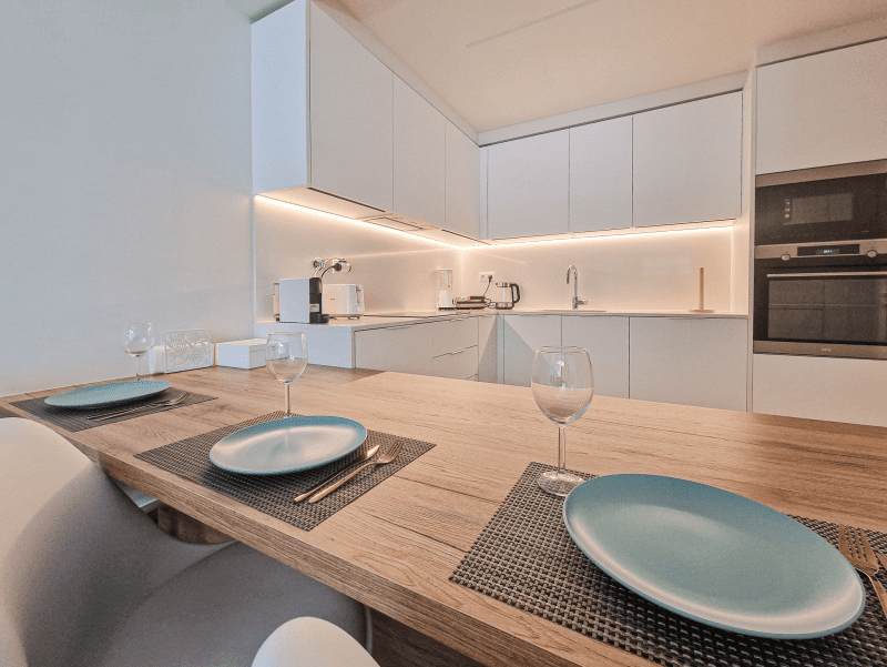 Bacalhau kitchen at Bayline, Armação de Pêra: white fitted kitchen and wooden dining table set for two