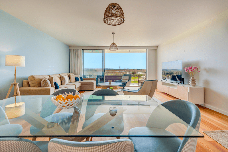 Enguia at Bayline, Armação de Pêra: glass dining table, with the living room and balcony beyond