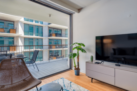 Peixe Balão living room at Bayline, Armação de Pêra: TV unit, rattan chair and open sliding doors to the balcony