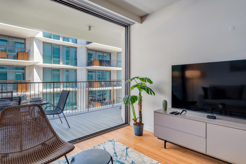 Peixe Balão living room at Bayline, Armação de Pêra: TV unit, rattan chair and open sliding doors to the balcony