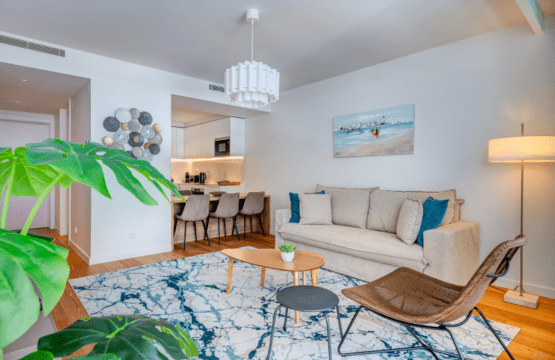 Peixe Balão at Bayline, Armação de Pêra: living room with sofa and rattan chair, dining area and kitchen behind