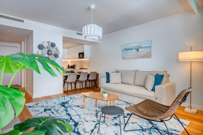 Peixe Balão at Bayline, Armação de Pêra: living room with sofa and rattan chair, dining area and kitchen behind