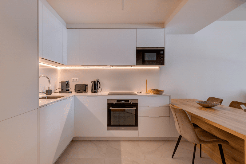 Peixe Balão kitchen at Bayline, Armação de Pêra: white fitted kitchen with built-in oven and wooden dining table
