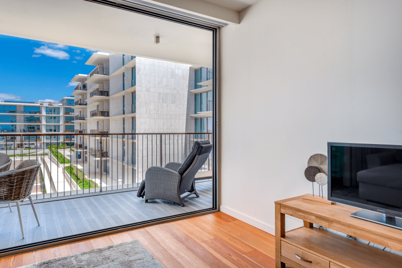 Corvina at Bayline, Armação de Pêra: open sliding door to the balcony with a lounge chair, TV unit inside