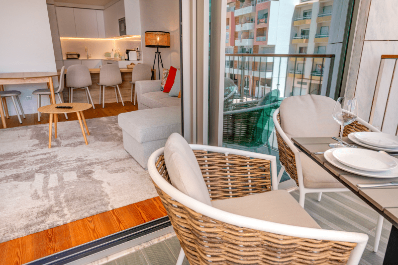 Corvina balcony at Bayline, Armação de Pêra: wicker chairs and a table set for two, living room beyond