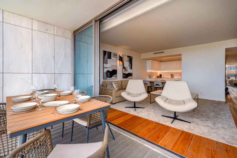 Ostra balcony at Bayline, Armação de Pêra: table set for dinner, with the living room seen through the open doors