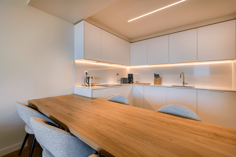 Ostra kitchen at Bayline, Armação de Pêra: white fitted kitchen and wooden dining table with grey chairs