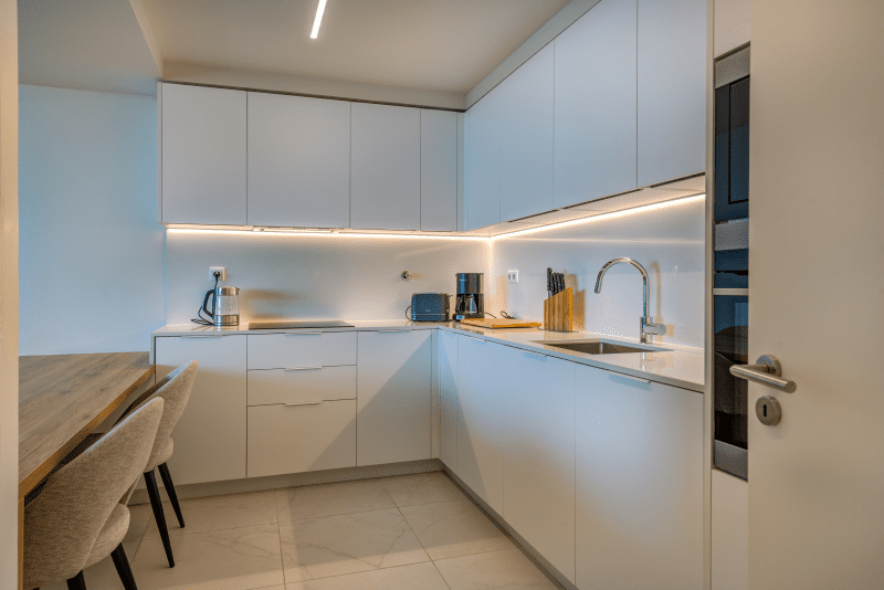 Ostra kitchen at Bayline, Armação de Pêra: white L-shaped kitchen with under-cabinet lighting
