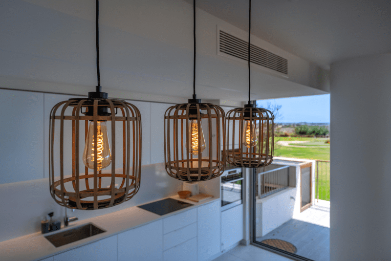 Sardinha kitchen at Bayline, Armação de Pêra: rattan pendant lights over a white kitchen, terrace door beyond