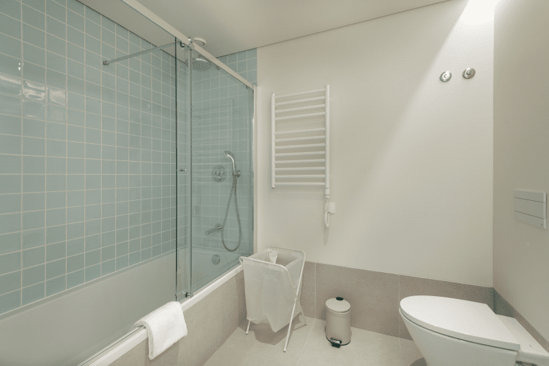 Sardinha bathroom at Bayline, Armação de Pêra: bathtub with glass screen, blue tiles and heated towel rail