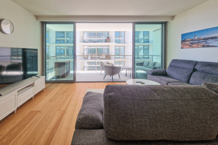 Bacalhau living room at Bayline, Armação de Pêra: grey corner sofa and glass doors to the balcony