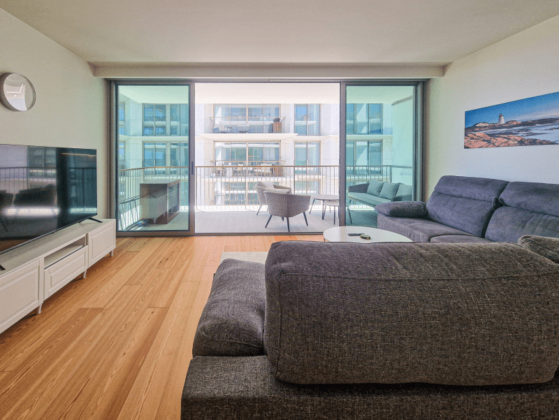 Bacalhau living room at Bayline, Armação de Pêra: grey corner sofa and glass doors to the balcony