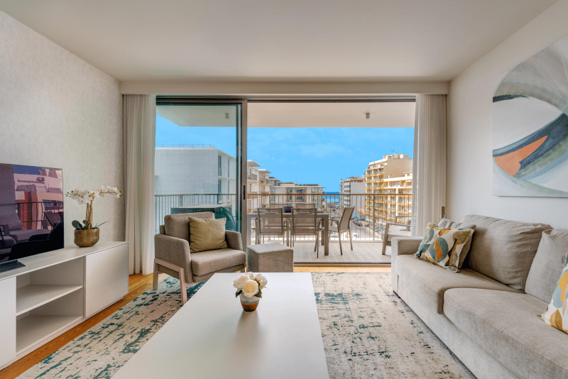 Safia living room at Bayline, Armação de Pêra: sofa, armchair and coffee table facing the balcony with dining table