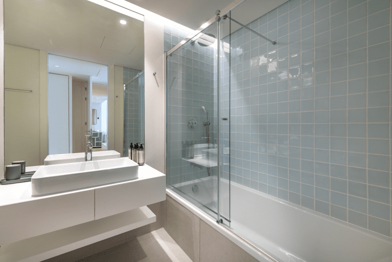 Safia bathroom at Bayline, Armação de Pêra: vessel basin and bathtub with glass screen and blue-grey tiles