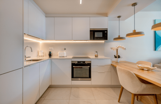 Liro kitchen at Bayline, Armação de Pêra: white fitted kitchen with built-in oven and wooden breakfast bar