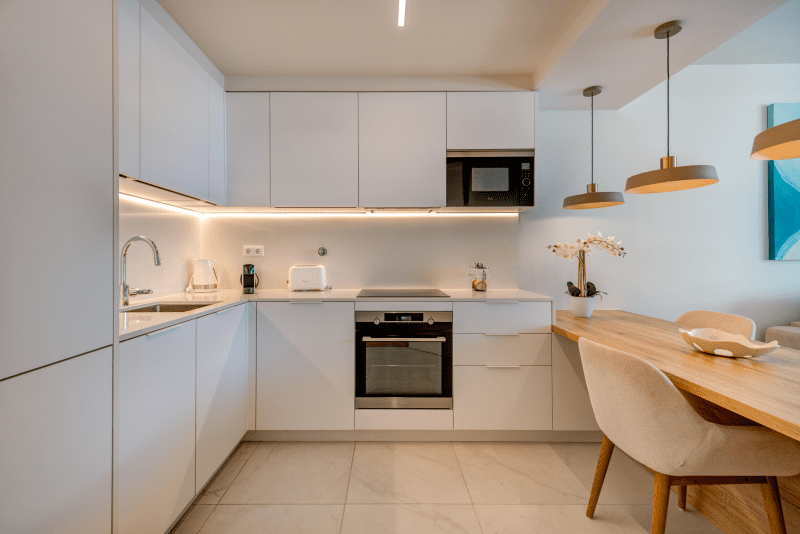 Liro kitchen at Bayline, Armação de Pêra: white fitted kitchen with built-in oven and wooden breakfast bar