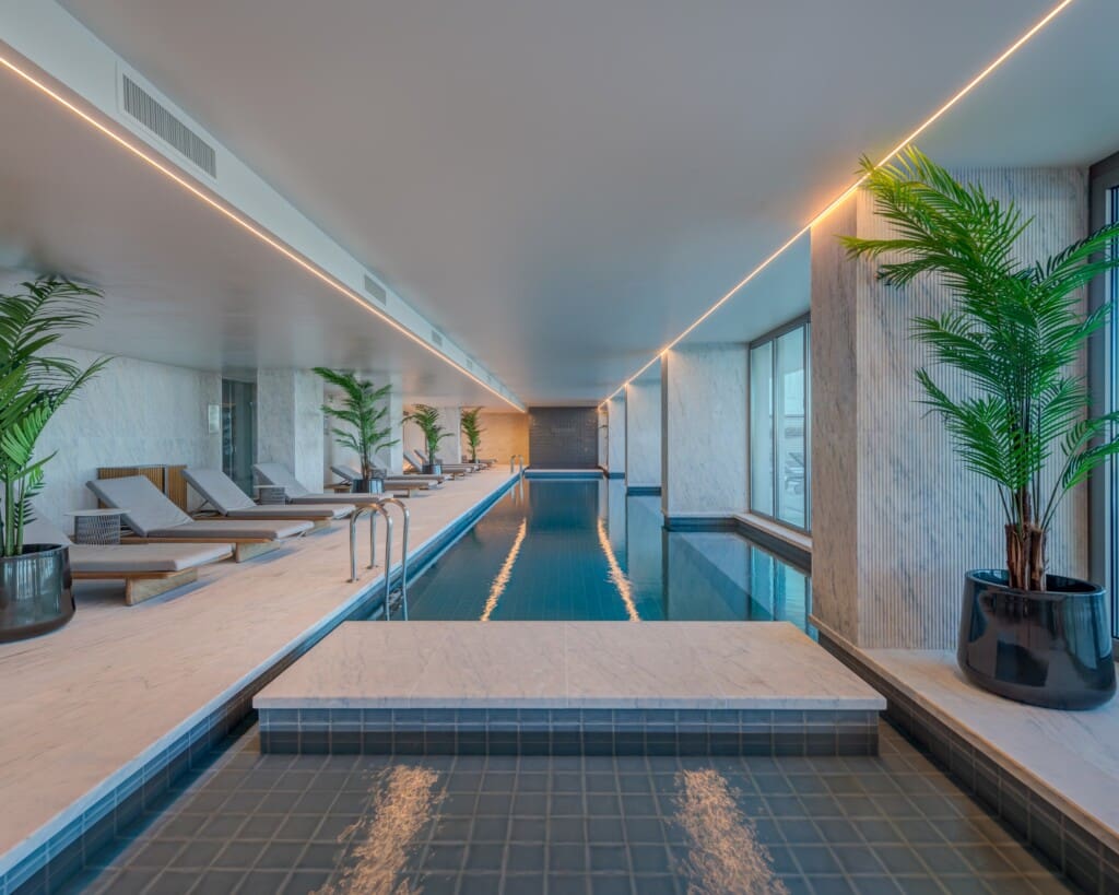 Bayline condominium indoor pool in Armação de Pêra: long pool lined with loungers and potted palms