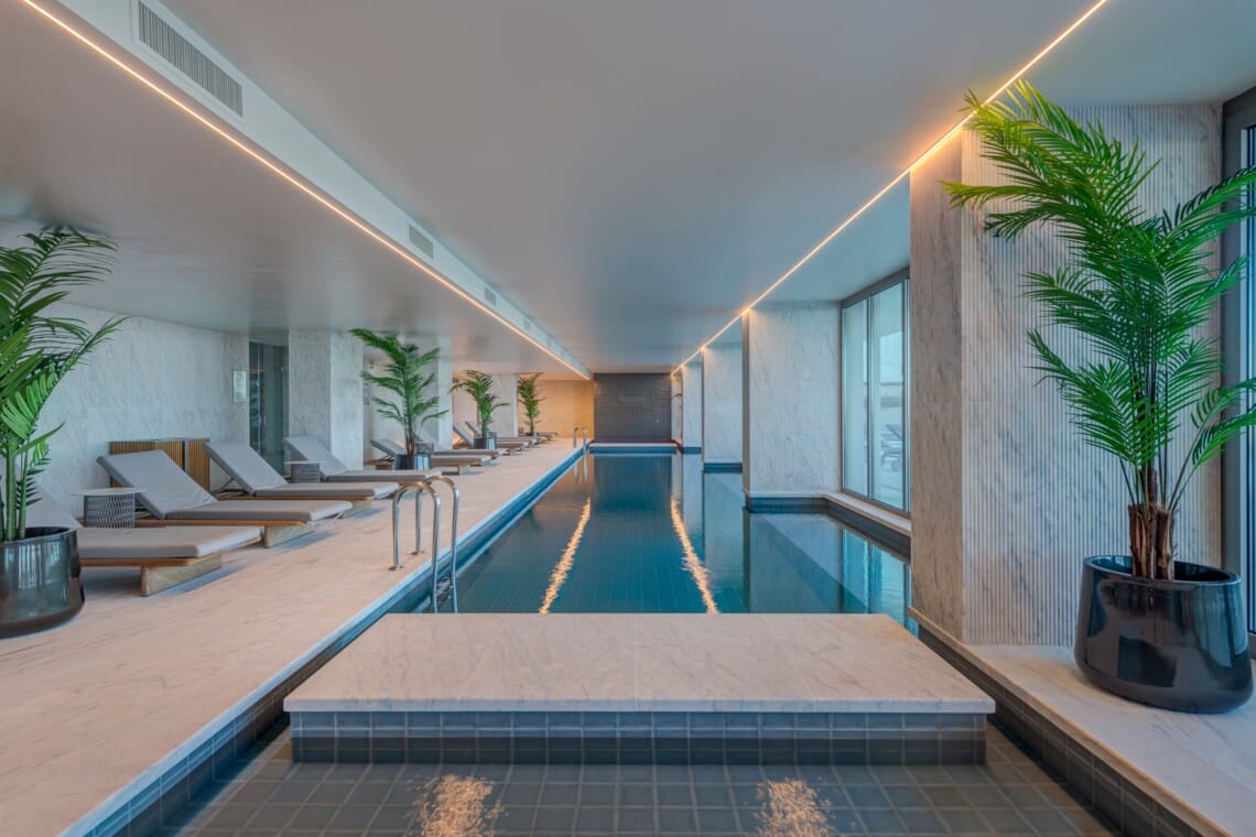Bayline condominium indoor pool in Armação de Pêra: long pool lined with loungers and potted palms