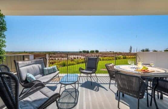 Pargo B terrace at Bayline, Armação de Pêra: lounge sofa and dining table set with drinks, gardens beyond