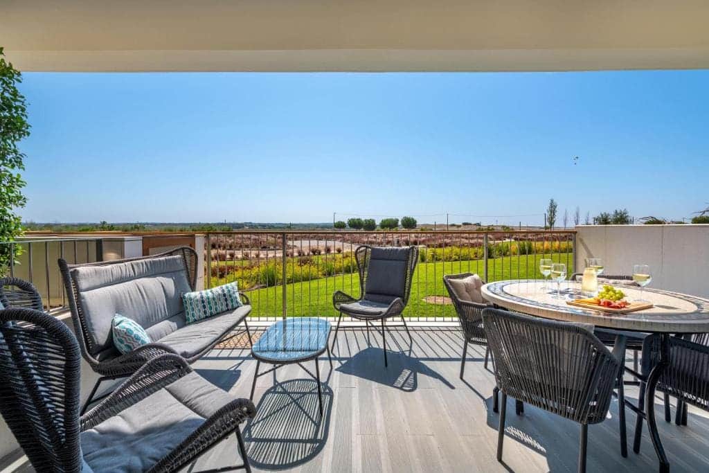 Pargo B terrace at Bayline, Armação de Pêra: lounge sofa and dining table set with drinks, gardens beyond