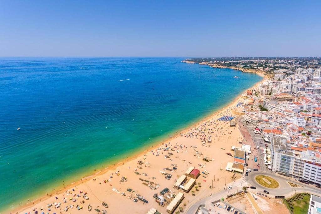Aerial view of a long sandy beach along a seaside town
