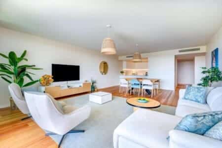 Pargo B living room at Bayline, Armação de Pêra: white sofa, swivel armchair and TV, dining area beyond