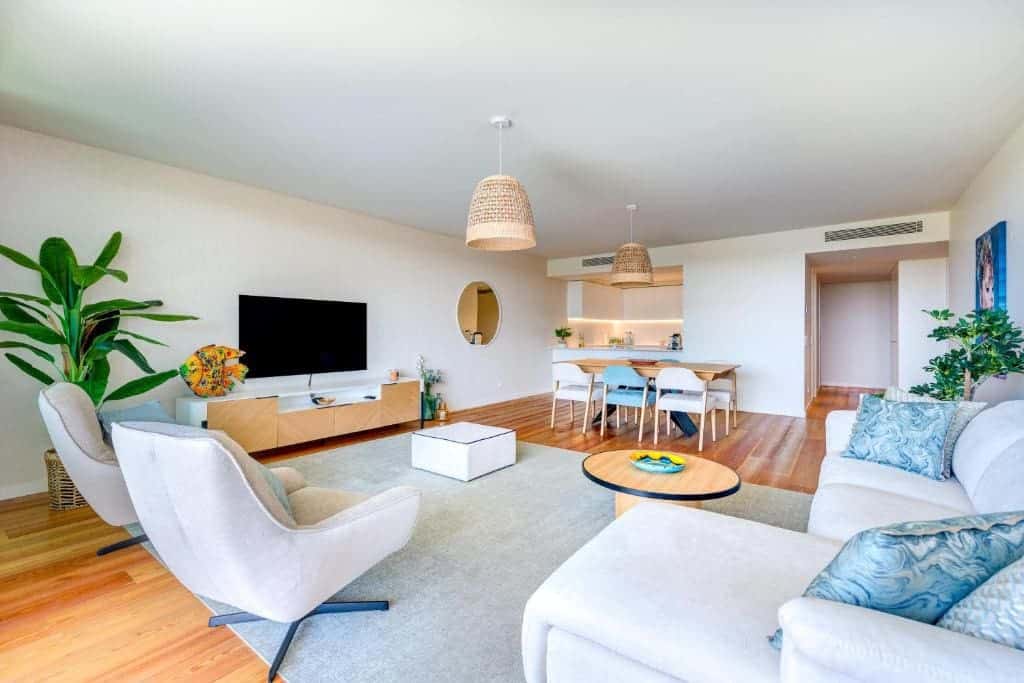 Pargo B living room at Bayline, Armação de Pêra: white sofa, swivel armchair and TV, dining area beyond