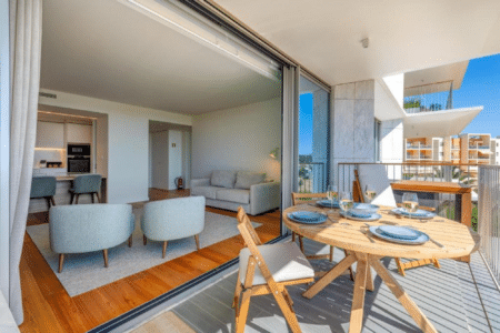 Nemo balcony at Bayline, Armação de Pêra: round wooden table laid for four, living room through the open doors